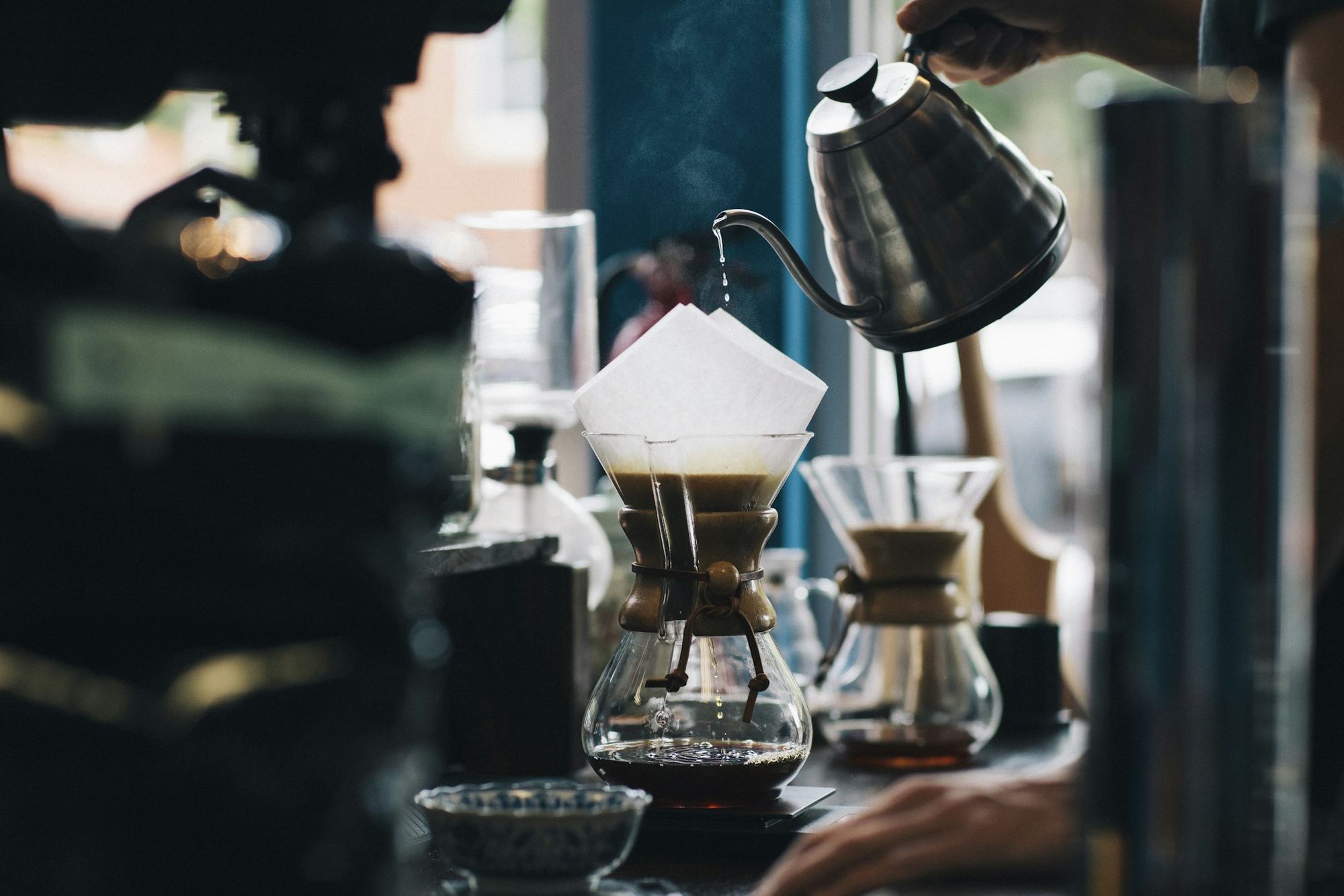 Barista pouring a slow pour-over in a dim coffee bar